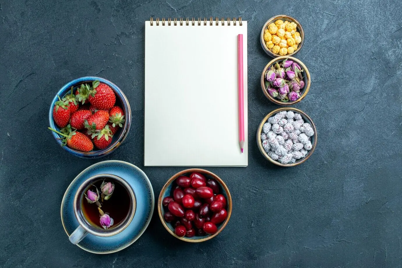 Draufsicht auf eine Tasse Tee mit Bonbons und Früchten auf grauem Hintergrund.